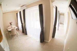 un pasillo con una mesa y una ventana con cortinas en Reforma Apartman, en Szerencs
