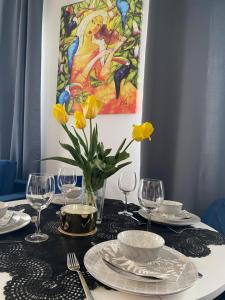 un tavolo con piatti, bicchieri da vino e fiori gialli di UniLove Apartamenty a Uniejow