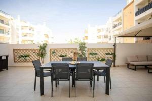 Une table à manger et des chaises noires sont disponibles sur la terrasse. dans l'établissement Modern 3br Apt w/ Lg Terrace, Bbq, Ac & Parking, à Tavira