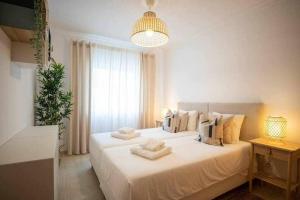 a bedroom with a large white bed with towels on it at Modern 3br Apt w/ Lg Terrace, Bbq, Ac & Parking in Tavira +24 photos