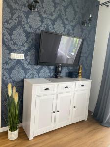 una televisione in cima a un armadio bianco in una stanza di UniLove Apartamenty a Uniejow