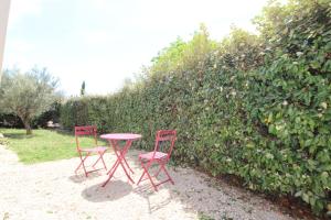 two red chairs and a table in front of a hedge at Charmant appartement calme à Paradou in Paradou