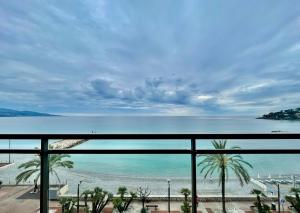 Una vista de una playa y el océano desde un balcón. en Appartement Le Schooner, en Roquebrune-Cap-Martin