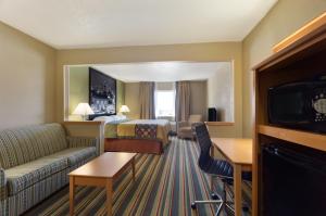 a hotel room with a bed and a couch and a tv at Super 8 by Wyndham Lees Summit in Lees Summit