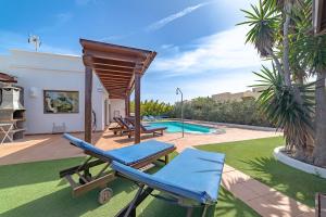 un patio con mesa, sillas y piscina en Villa Alegria, en Playa Blanca