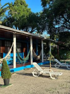 a house with hammocks and a bench in front of it at Pousada Pé Na Areia - ilha do mel in Paranaguá