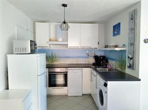a kitchen with white cabinets and a white refrigerator at Strukkamp "Inselmädchen" Strukkamp in Fehmarn