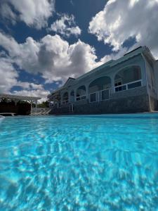 una grande piscina con acqua blu di fronte a un edificio di Glacière Paradise a Bouillante