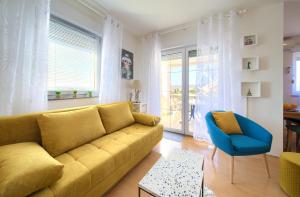 sala de estar con sofá amarillo y silla azul en Apartman Noel, en Krk