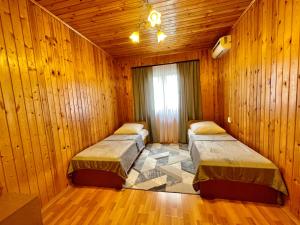 2 camas en una habitación con paredes de madera en Дом под ключ Комфортик en Gagra