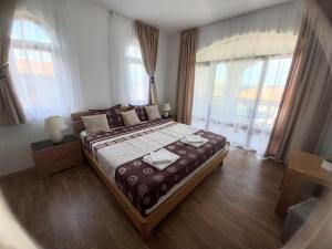 a bedroom with a large bed in a room with windows at Къща за гости Мускат 2 in Aheloy +149 photos