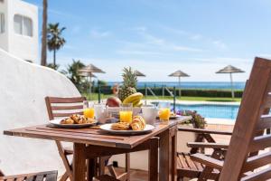 ein Holztisch mit Frühstücksspeisen und Getränken auf einer Terrasse in der Unterkunft Rocas del Mar in Mijas