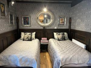 a bedroom with two beds and a mirror on the wall at 8 Opera Suites, Llangollen in Llangollen