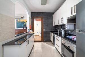 a kitchen with white cabinets and black counter tops at Villa Alegria in Playa Blanca