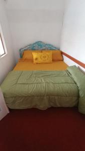 un letto in una piccola camera con cuscino giallo di Rumah Gadang Simarasok a Baso
