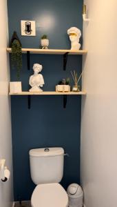 a bathroom with a blue wall and a toilet with shelves at Une terrasse sur la mer in Crozon