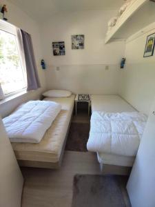 um pequeno quarto com 2 camas e uma janela em Vakantiehuis Hollum Ameland dichtbij strand en met ruime tuin - Ameland39 nl em Hollum
