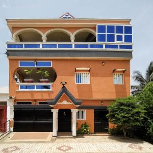 an orange building with blue windows and a garage at Agbata Guest House 