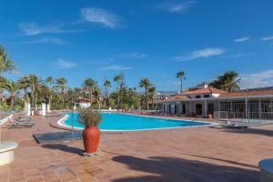 ein Pool mit Palmen und ein Gebäude in der Unterkunft Lightbooking Sun Club Playa Ingles 2 habitaciones in Maspalomas