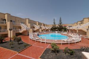 a large courtyard with a swimming pool in a building at Lightbooking Las Arenas Caleta de Fuste in Caleta De Fuste