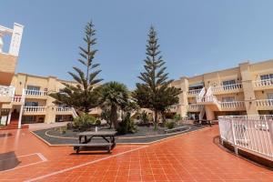 a courtyard with a picnic table in front of a building at Lightbooking Las Arenas Caleta de Fuste in Caleta De Fuste