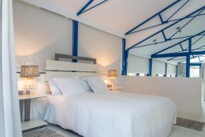 um quarto com uma cama branca e uma mesa em Lightbooking Praia Fabrica Algarve em Vila Nova de Cacela