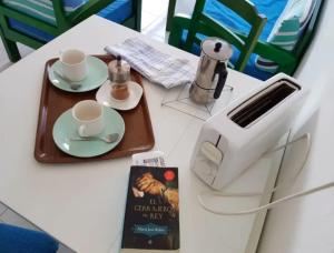 a table with two cups and a toaster and a book at Lightbooking Los Lagos El Cotillo in El Cotillo