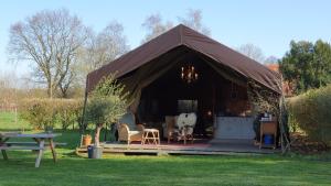 Tenda con tavolo e sedie in un campo di Luxe tent op het platteland a Nieuwediep