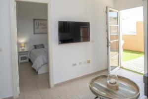 カレタ・デ・フステにあるLightbooking Esmeralda Calete de Fuste FUEの壁にテレビとベッドが備わる客室です。