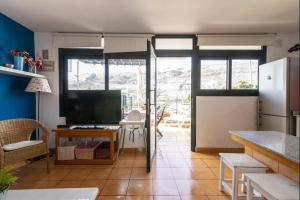 a kitchen with a refrigerator and a table with a television at Lightbooking Arizona Puerto Rico in Puerto Rico de Gran Canaria