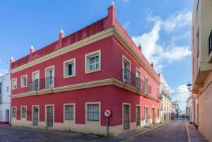 un edificio rojo al lado de una calle en Lightbooking Mazarredo San Fernando, en San Fernando