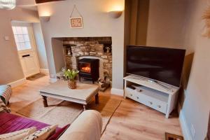 a living room with a fireplace and a flat screen tv at Hideaway Cottage Sleaford in Sleaford +6 photos