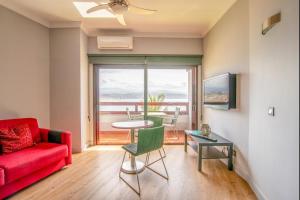 a living room with a red couch and a table at Lightbooking Las Canteras Beach Sea View in Las Palmas de Gran Canaria