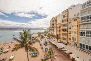 a view of a beach with palm trees and buildings at Lightbooking Las Canteras Beach Sea View in Las Palmas de Gran Canaria