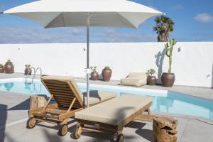 テルデにあるLightbooking Edem Playa del Hombreのスイミングプールの横に椅子とパラソルがあります。