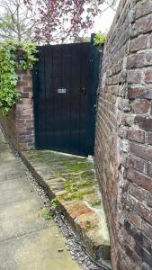 una puerta negra en el lateral de una pared de ladrillo en The Coach House en Bewdley