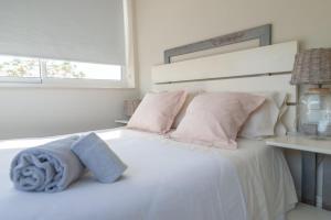ein Schlafzimmer mit einem weißen Bett mit rosa Kissen in der Unterkunft Lightbooking Praia Fabrica Algarve in Vila Nova De Cacela