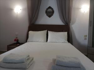 a bedroom with a white bed with two towels on it at Halkidiki Rooms in Nea Fokea