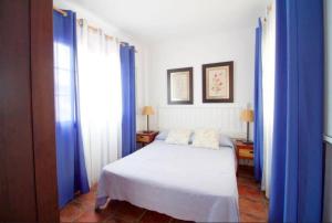 1 dormitorio con cortinas azules y 1 cama blanca en Lightbooking La Graciosa, en Caleta de Sebo