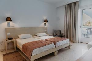 a bedroom with a bed and a large window at Hotel Bougainvillier Djerba in Taguermess