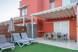 a patio with a table and chairs and an umbrella at Lightbooking piscina privada Salobre Golf in San Bartolomé