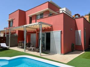 a red house with a swimming pool in front of it at Lightbooking piscina privada Salobre Golf in San Bartolomé