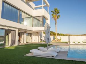Una gran casa blanca con una piscina y una palmera en Lightbooking Montecastillo Moto GP en Jerez de la Frontera