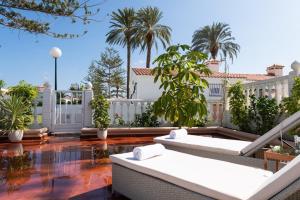 patio z białymi ogrodzeniami i palmami w obiekcie Lightbooking Santa Barbara Playa del Ingles w mieście Maspalomas