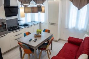 eine Küche mit einem Tisch und einem roten Sofa in der Unterkunft Appartamento Vale Mare Vista Canale in Chioggia