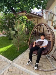 a young man sitting in a wicker swing at Hotel Han in Samarkand