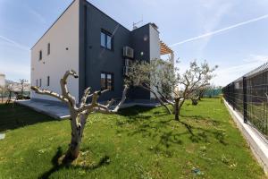 a black and white house with two trees in the yard at Villa C'est la vie in Kaštela