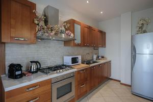 uma cozinha com armários de madeira e um frigorífico branco em Nadia Green House em Ganfardine