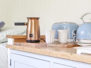 a counter with a coffee pot and glasses on it at Gwithian Shepherds Hut in Hayle