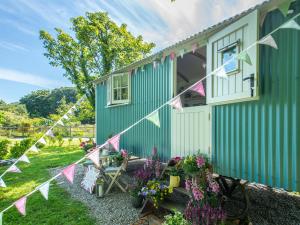 a green house with pink and white flags on it at Gwithian Shepherds Hut in Hayle